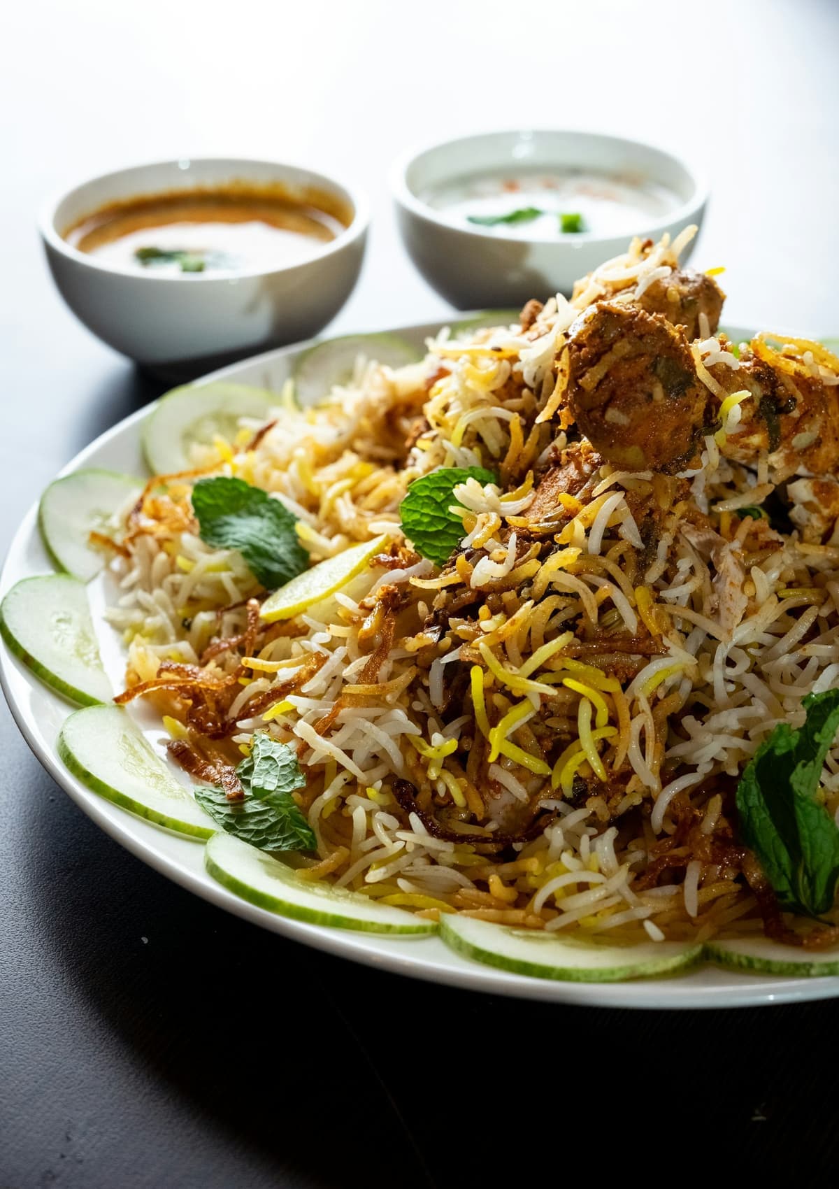 Platter of biryani garnished with mint and cucumber