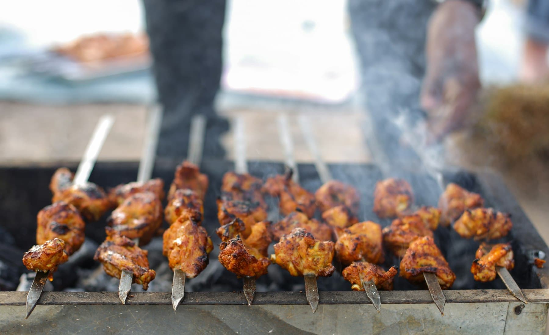 Skewers of marinated chicken grilling over charcoal